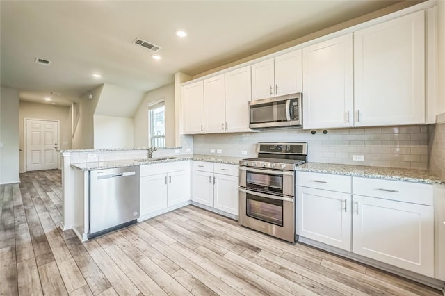 10401 American Paint Way, Manor, TX 78653 - kitchen featuring stainless steel appliances, a sink, light wood-style floors, white cabinetry, and backsplash