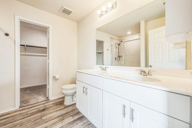 10401 American Paint Way, Manor, TX 78653 - bathroom featuring a walk in closet, wood finished floors, double vanity, and a stall shower