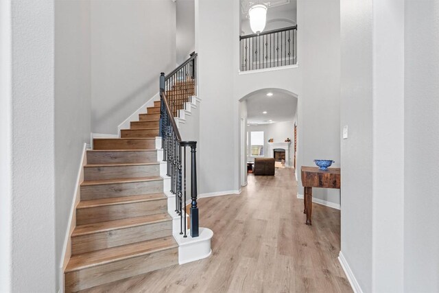 3912 Walsh Ranch Blvd, Round Rock, TX 78681 - entrance foyer with arched walkways, wood finished floors, stairway, a towering ceiling, and a fireplace