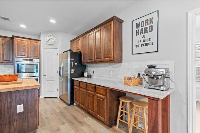 3912 Walsh Ranch Blvd, Round Rock, TX 78681 - kitchen featuring stainless steel appliances, decorative backsplash, a kitchen breakfast bar, light wood-style floors, and wood counters