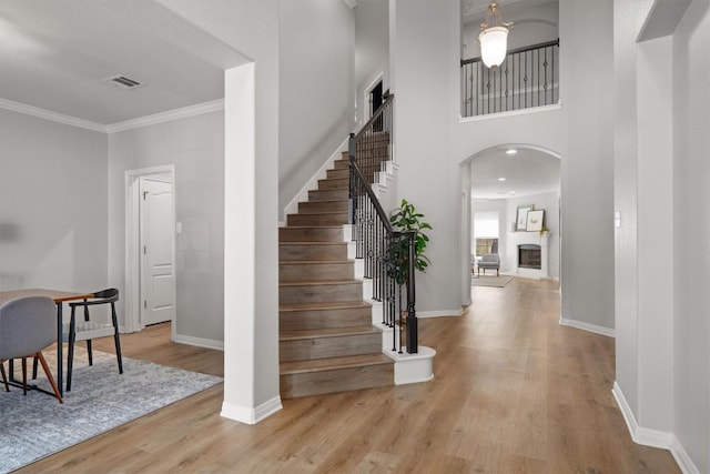 3912 Walsh Ranch Blvd, Round Rock, TX 78681 - foyer with light wood-style flooring, arched walkways, stairway, ornamental molding, and a fireplace