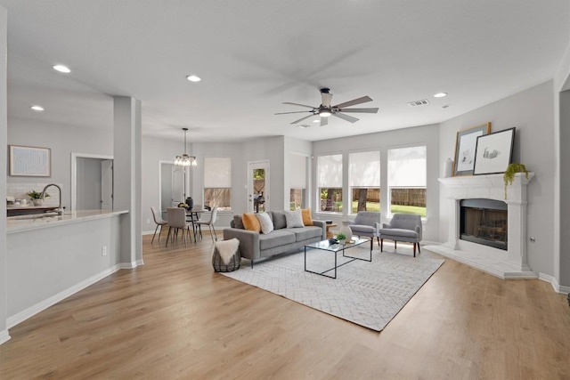 3912 Walsh Ranch Blvd, Round Rock, TX 78681 - living room featuring ceiling fan, a fireplace with raised hearth, recessed lighting, light wood-type flooring, and a chandelier