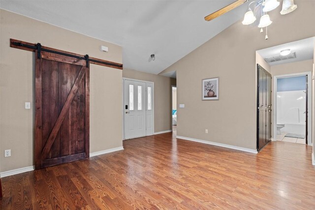 102 Vandeventer Dr, Burnet, TX 78611 - unfurnished living room with a ceiling fan, vaulted ceiling, a barn door, wood finished floors, and baseboards