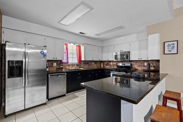102 Vandeventer Dr, Burnet, TX 78611 - kitchen featuring appliances with stainless steel finishes, a sink, a peninsula, white cabinets, and decorative backsplash