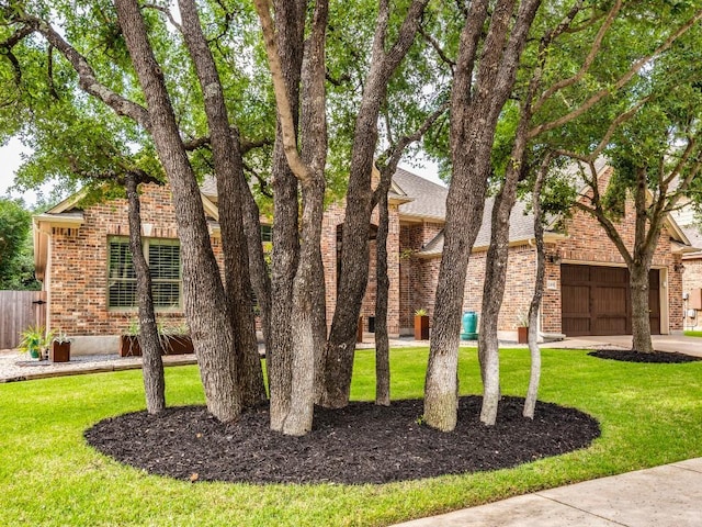 view of front facade featuring brick siding, an attached garage, fence, and a front yard
