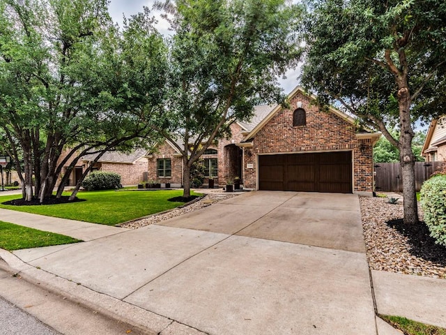 view of front of home with fence, an attached garage, brick siding, a front yard, and driveway
