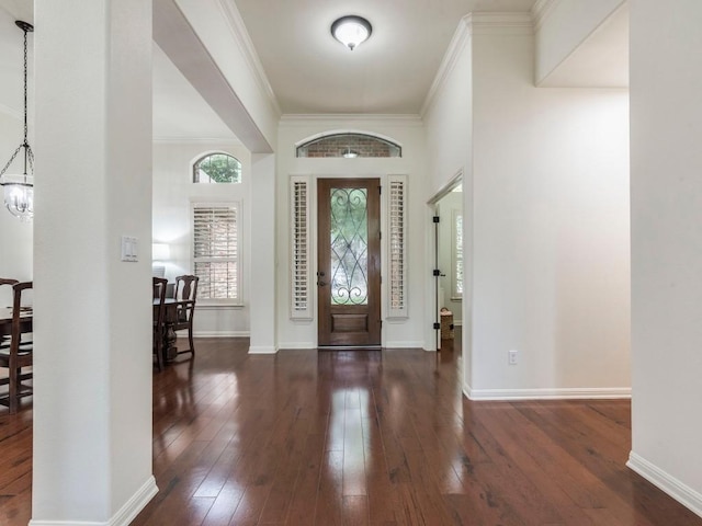foyer entrance featuring baseboards, ornamental molding, a notable chandelier, and hardwood / wood-style flooring