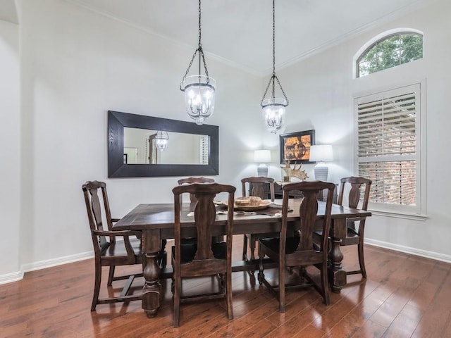 dining area with dark wood-type flooring, baseboards, crown molding, and an inviting chandelier