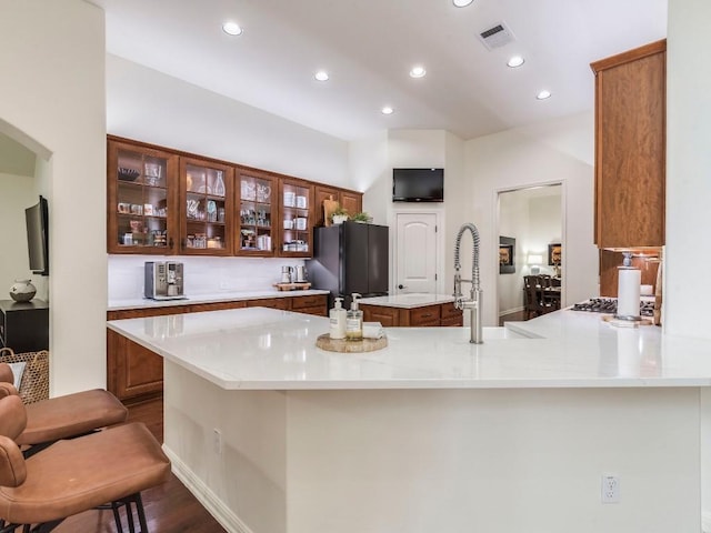 kitchen featuring dark wood finished floors, freestanding refrigerator, recessed lighting, visible vents, and glass insert cabinets