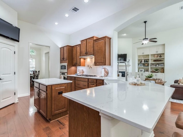 kitchen with visible vents, a ceiling fan, a center island, a sink, and stainless steel appliances