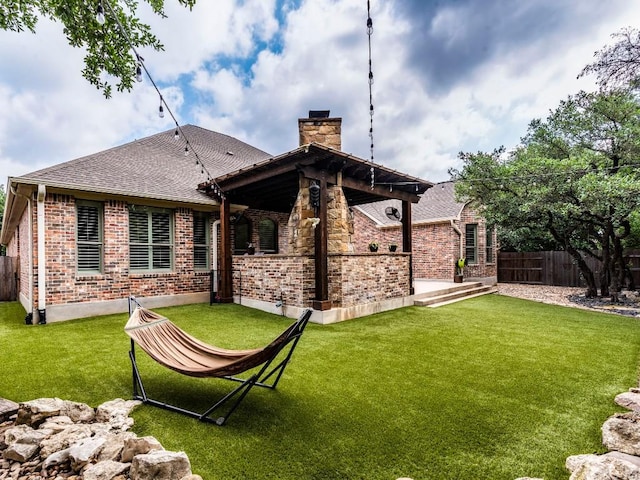 rear view of house featuring fence, a chimney, a lawn, and brick siding