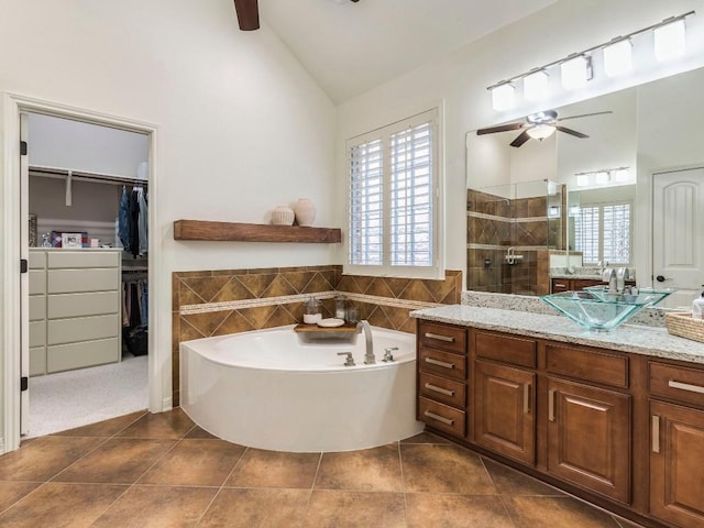 bathroom with vanity, ceiling fan, a bath, tile patterned floors, and a tile shower