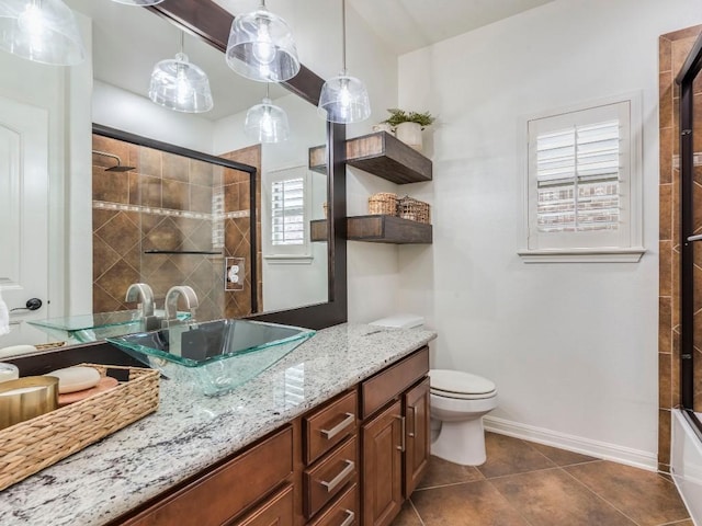 bathroom with tile patterned flooring, vanity, toilet, baseboards, and a tile shower