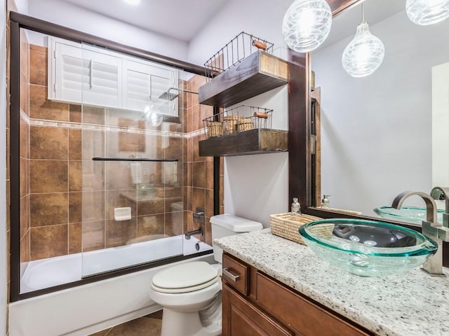 bathroom with shower / bath combination with glass door, tile patterned flooring, toilet, and vanity
