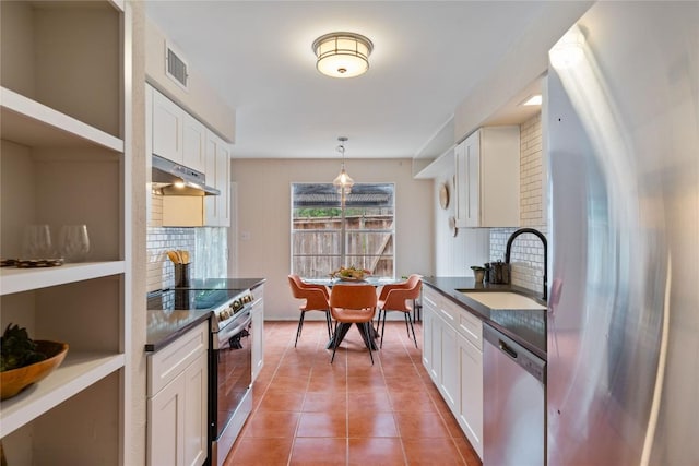7253 Creekside Dr, Austin, TX 78752 - kitchen featuring under cabinet range hood, dark countertops, appliances with stainless steel finishes, and a sink