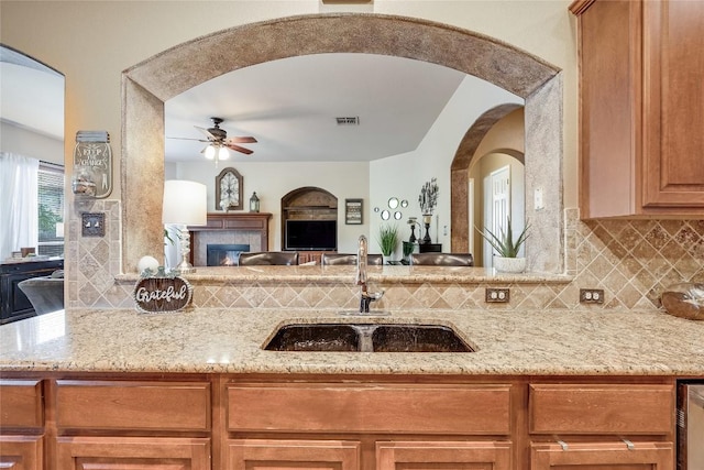 kitchen with a ceiling fan, visible vents, arched walkways, tasteful backsplash, and a sink
