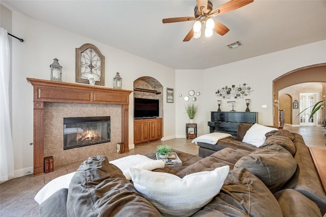 2607 Armatrading Dr, Cedar Park, TX 78613 - living room with arched walkways, a ceiling fan, light tile patterned floors, a tiled fireplace, and baseboards