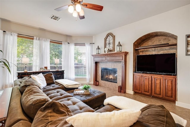living area featuring visible vents, a ceiling fan, a wealth of natural light, and a tile fireplace