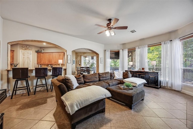 living room featuring visible vents, arched walkways, a ceiling fan, and light tile patterned floors