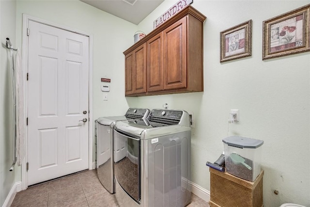 clothes washing area with independent washer and dryer, baseboards, light tile patterned floors, and cabinet space