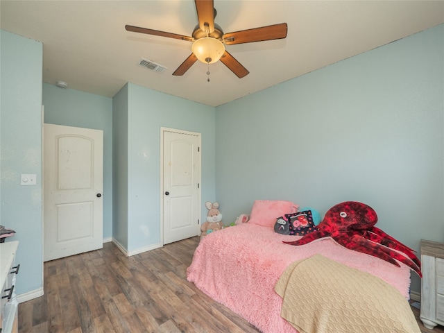 bedroom featuring visible vents, baseboards, ceiling fan, and wood finished floors