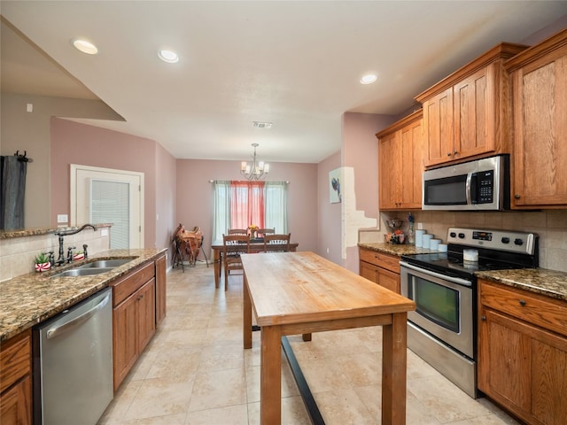 419 Spyglass St, Marble Falls, TX 78654 - kitchen with stainless steel appliances, tasteful backsplash, brown cabinetry, a sink, and dark stone countertops