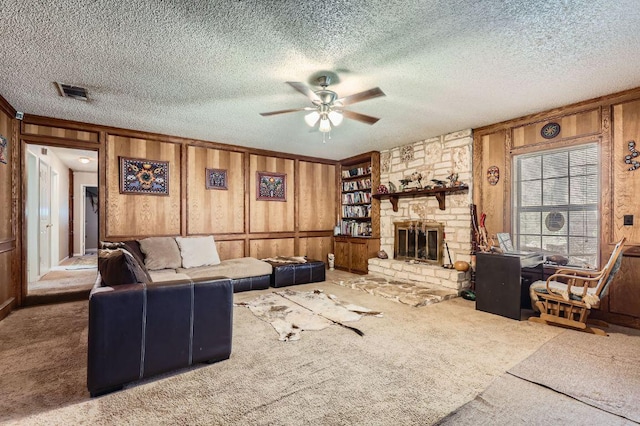 living area with visible vents, carpet flooring, a ceiling fan, and wood walls