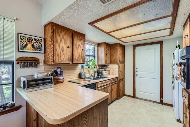 kitchen with brown cabinets, light countertops, light floors, a peninsula, and a toaster