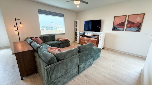 living area featuring a ceiling fan, baseboards, and light wood-style floors