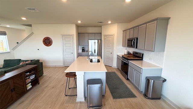 kitchen with a sink, appliances with stainless steel finishes, gray cabinets, and visible vents