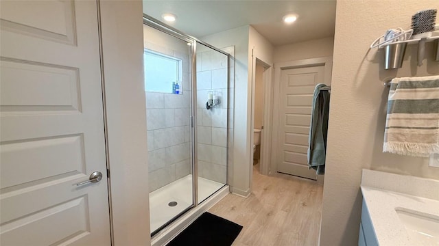 bathroom with recessed lighting, a shower stall, toilet, and wood finished floors