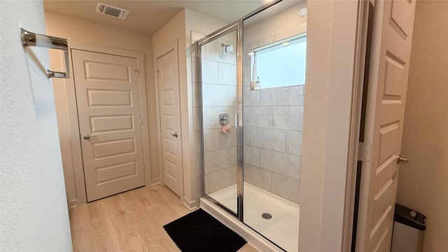 full bathroom featuring visible vents, wood finished floors, and a stall shower