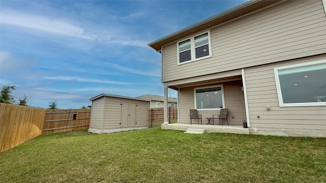rear view of house with a storage unit, a fenced backyard, an outbuilding, a lawn, and a patio