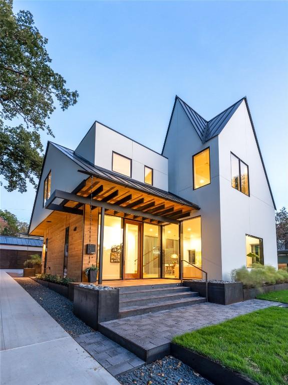 rear view of house with a standing seam roof, stucco siding, and metal roof