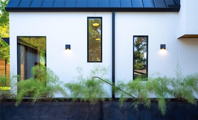 view of side of property with a standing seam roof, stucco siding, and metal roof