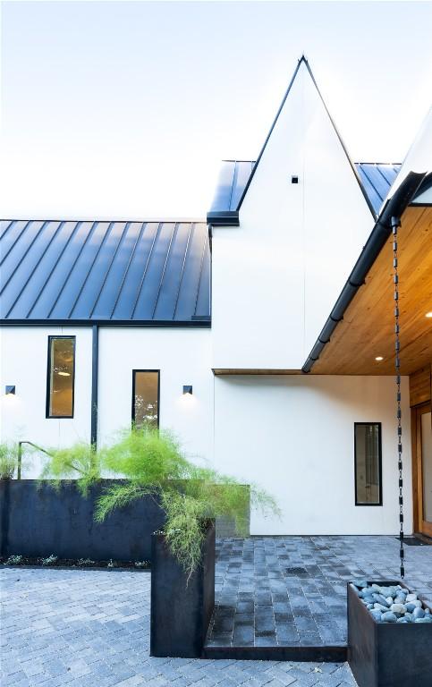 view of property exterior featuring a patio, a standing seam roof, metal roof, and stucco siding
