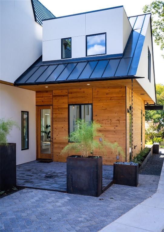back of house featuring a standing seam roof, metal roof, and stucco siding