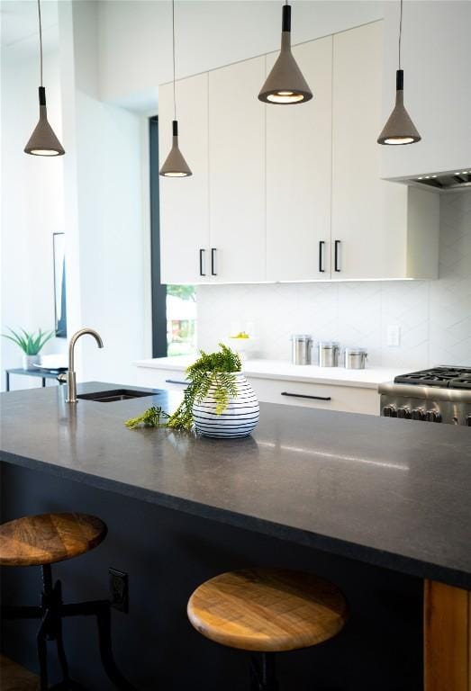 kitchen featuring pendant lighting, a kitchen breakfast bar, backsplash, and white cabinets