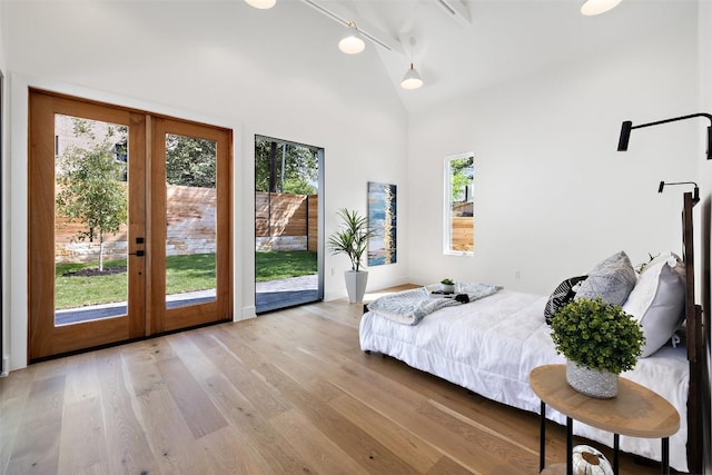 bedroom with rail lighting, access to outside, french doors, and light wood-type flooring