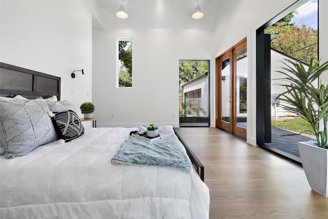 bedroom featuring access to outside, baseboards, wood finished floors, and french doors