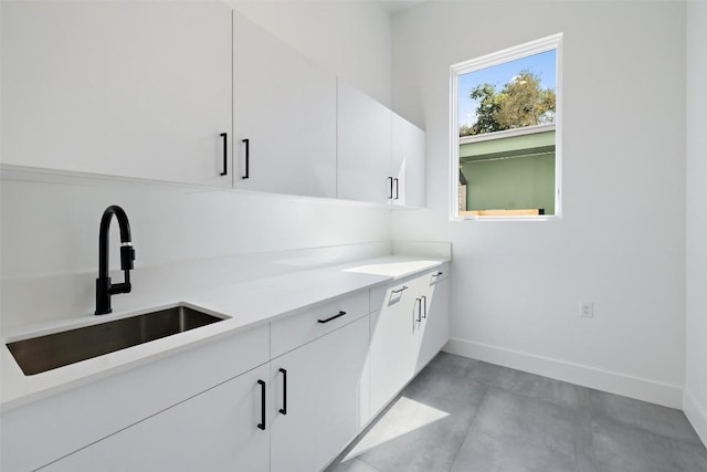 interior space with a sink, light countertops, white cabinetry, baseboards, and modern cabinets