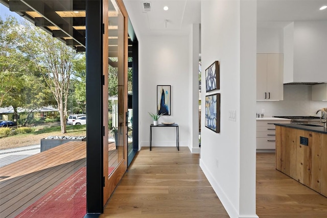corridor featuring baseboards, visible vents, plenty of natural light, and light wood-style floors
