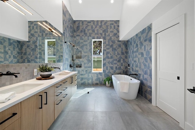 bathroom with double vanity, tile walls, a sink, a walk in shower, and a soaking tub