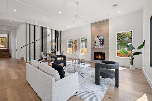 living area with visible vents, a fireplace, stairs, light wood finished floors, and recessed lighting