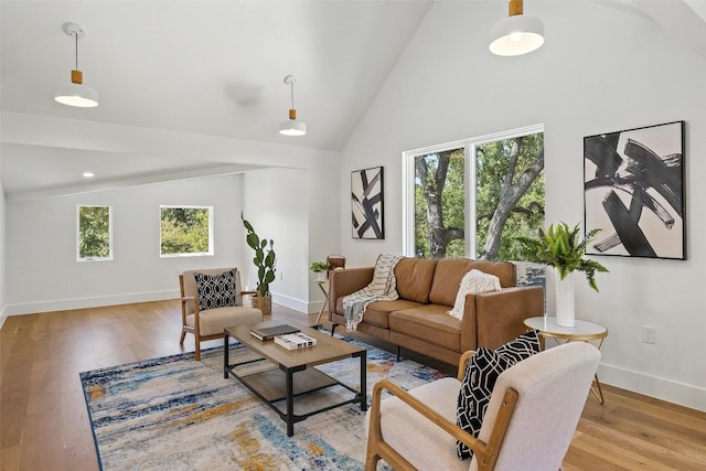 living room featuring baseboards, light wood finished floors, and high vaulted ceiling