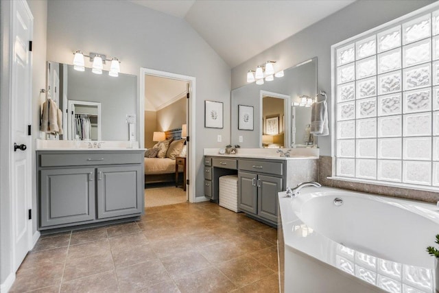 ensuite bathroom featuring a garden tub, ensuite bath, lofted ceiling, and vanity