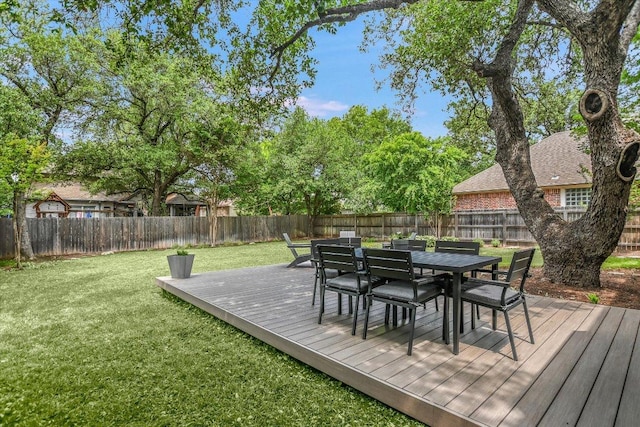 wooden terrace with a lawn, outdoor dining area, and a fenced backyard