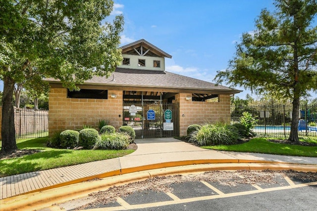 doorway to property with a community pool, fence, a shingled roof, and uncovered parking
