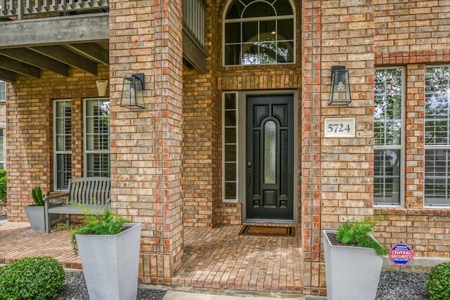 view of exterior entry with brick siding and a porch