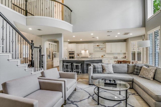 living room featuring a high ceiling, visible vents, and a wealth of natural light